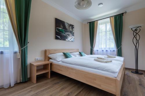 a bedroom with a bed with white sheets and green curtains at Penzion Pod Krásnou horou in Benešov nad Černou