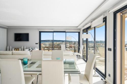 une salle à manger avec une table en verre et des chaises blanches dans l'établissement 5 Bedroom Cannes Penthouse - Ocean View, à Cannes