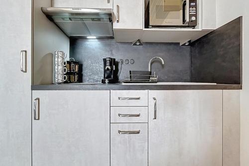 Una cocina con gabinetes blancos y un fregadero. en Le Neptune - Studio face à la plage - Parking, en Fleury