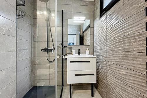 une salle de bain avec un lavabo blanc et une douche dans l'établissement Le Neptune - Studio face à la plage - Parking, à Fleury