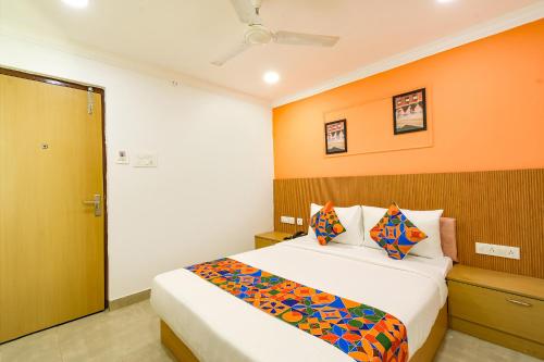a bedroom with a bed with an orange wall at Fabhotel Cinco Primera Nr LV Prasad, Banjara Hills in Hyderabad