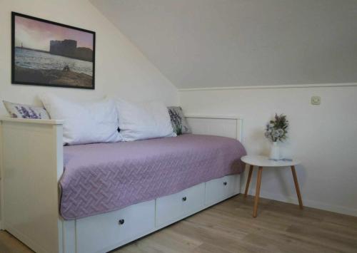 een slaapkamer met een bed met paarse lakens en een tafel bij Ledinić room in Mokošica