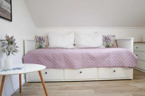 een wit bed met een roze dekbed en een tafel bij Ledinić room in Mokošica