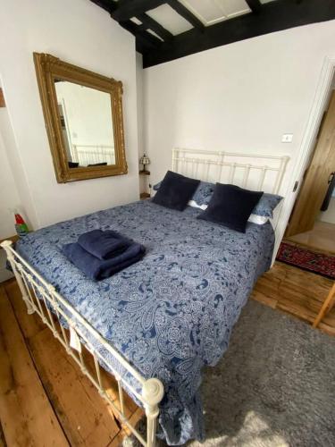 a bedroom with a bed with a blue blanket and a mirror at The Pepper Pot Sleeps 4 Sunlit Garden in Exmouth