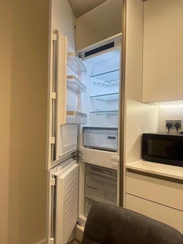 an empty refrigerator with its door open in a kitchen at The Verulam Retreat in St. Albans