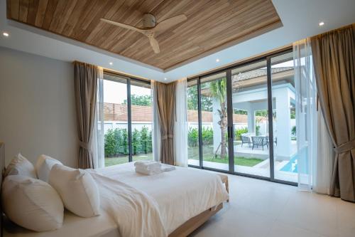 a bedroom with a bed and a large window at Mouana Breeze Mai Khao 4-bedroom Pool Villa 9918 in Mai Khao Beach