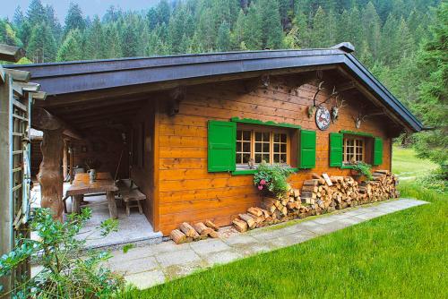 a log cabin with a green window and a pile of logs at Jagdhütte Hubertus in Silbertal