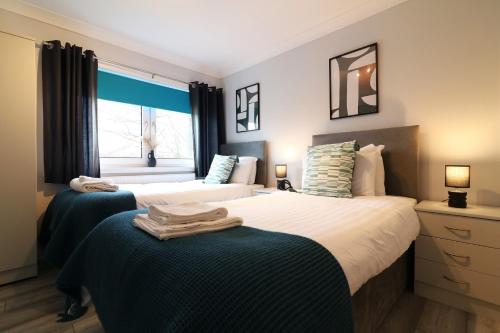 two beds in a bedroom with a window at Signature - Drumvale House in Chryston