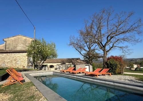 une piscine avec des chaises orangées et un bâtiment dans l'établissement Mas Constantin - piscine, jeux pour enfants et vue sur les montagnes, à Montboucher-sur-Jabron