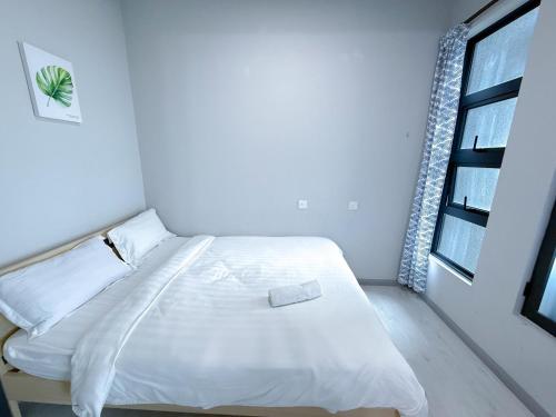 a white bed in a room with a window at 适合全家入住 Jesselton Quay高楼层日落景公寓 近Suria & Gaya街 Perfect for Families High-Floor Sunset Condo at Jesselton Quay Near Suria and Gaya Street in Kota Kinabalu