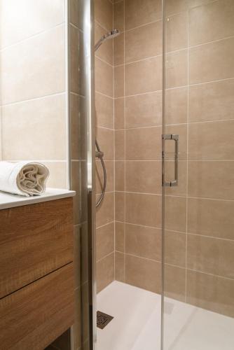 une douche avec une porte vitrée dans une salle de bain dans l'établissement Village de Gîtes de La Canourgue, à La Canourgue