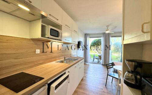 - une cuisine avec des placards blancs et un comptoir avec un évier dans l'établissement Studio Pinea Les pieds dans l'eau CALVI, à Calvi