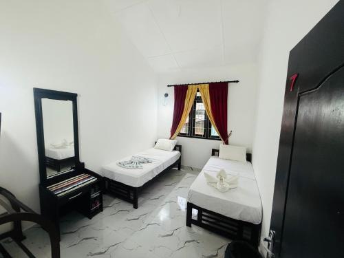 a small room with two beds and a mirror at St Jude Holiday Resort in Talawakele