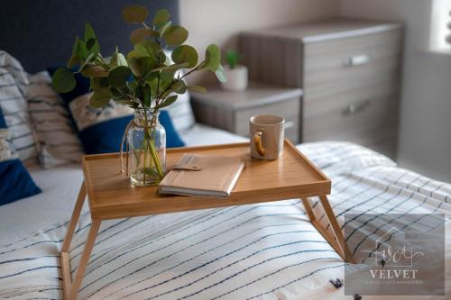un tavolo di legno con un libro e una tazza su un letto di 1 Bed House , Free WiFi,Free Parking,Leasure,Business a Swansea