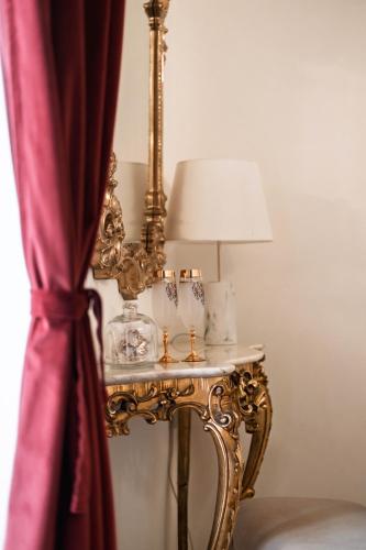 a gold end table with a lamp and a table with a lampurrection at Beretti Home in Catania