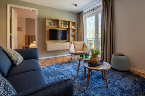 a living room with a blue couch and a tv at Residence Noordstaete - Vakantieappartement Lepelaar de Luxe in Burgh Haamstede