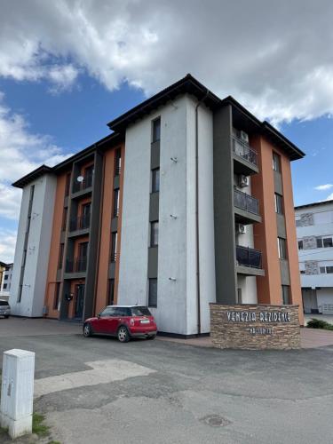 a red car parked in front of a building at Luxury Apartment with Private Parking in Giroc