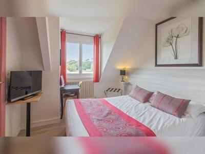 a bedroom with a bed and a flat screen tv at The Originals Boutique, Hôtel Les Quatre Salines, Le Mont Saint-Michel Sud in Roz-sur-Couesnon