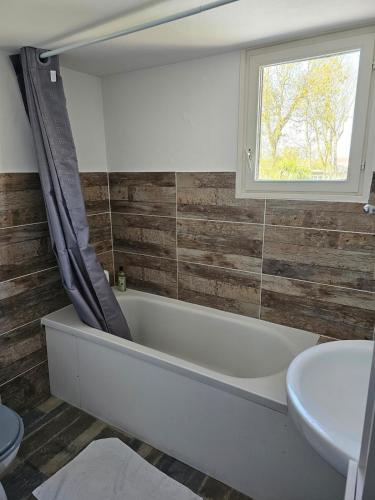 une salle de bain avec une baignoire, un lavabo et une fenêtre dans l'établissement Normandy house, sea and countryside - countryside - Cyrano gîte, à Ver-sur-Mer