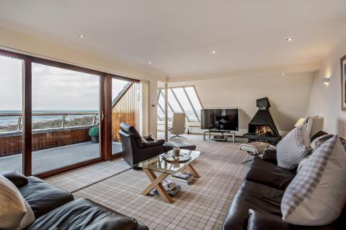 a living room with a couch and a table and a tv at Penthouse Golf View Apartments in Lossiemouth