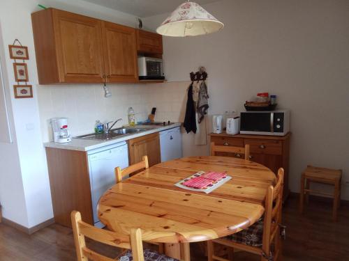 Il comprend une cuisine avec une table en bois et un évier. dans l'établissement Studio cabine cosy, balcon & parking, 05250 La Joue du Loup - FR-1-504-256, à Saint-Étienne-en-Dévoluy