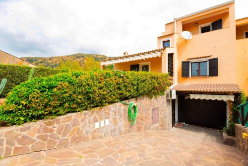 a house with a stone wall and a garage at dépendance President villa Tuerredda in Chia