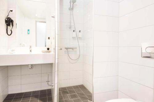 a white bathroom with a shower and a sink at Scandic Byporten in Oslo