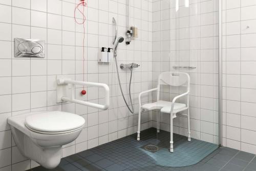 a bathroom with a shower with a toilet and a chair at Scandic Oslo Airport in Gardermoen