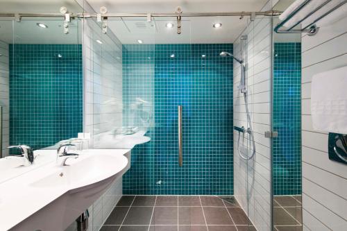 a bathroom with two sinks and a shower with blue tiles at Scandic Narvik in Narvik