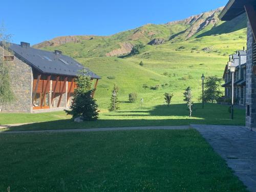 a house with a green hill in the background at Chalet Anayet Lodge Luxury 5 Stars in Formigal in Formigal