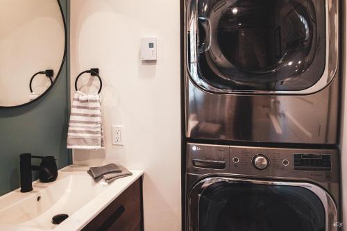 a bathroom with a washer and dryer next to a sink at Le Pignon Vert in Sainte-Séraphine