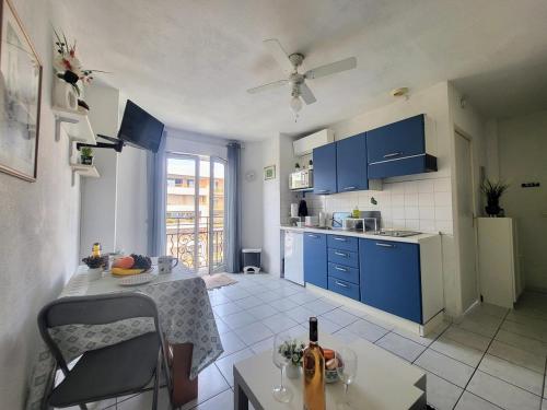 - une cuisine avec des placards bleus et une table avec une bouteille de vin dans l'établissement Valery Close to beach Prom des Anglais Ideal for 2 AC, à Nice