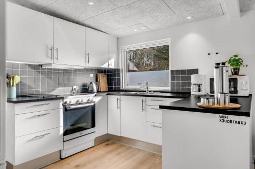 a kitchen with white cabinets and black counter tops at Holiday Home With Pool And Spa Close To The Limfjord in Roslev