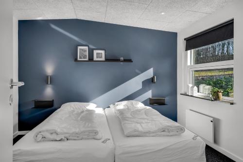 a room with two beds with a blue wall at Holiday Home With Pool And Spa Close To The Limfjord in Roslev