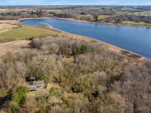an aerial view of a house next to a lake at Holiday Home With Pool And Spa Close To The Limfjord in Roslev
