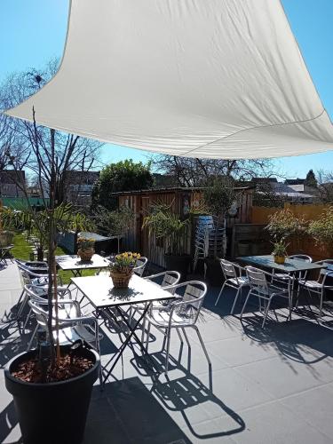 a patio with tables and chairs under a white umbrella at ' t Geel Huizeken - B&B - koffiehuis in Denderleeuw
