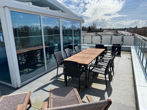 a patio with a wooden table and chairs on a roof at Appartementhäuser Achterwasserblick in Ostseebad Koserow