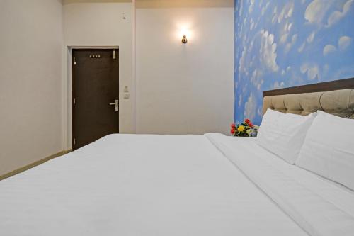 a large white bed in a room with a door at Capital O Maharana Palace in Udaipur