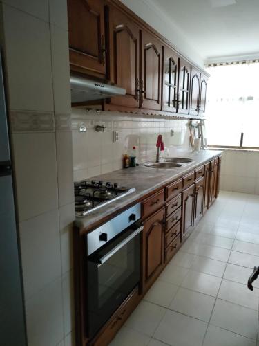 a kitchen with wooden cabinets and a stove top oven at Apartamento T2 Amorosa Beach in Viana do Castelo