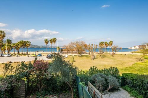 une vue sur un parc avec des palmiers et l'océan dans l'établissement Appartement La Perle Marine - Welkeys, à Cogolin