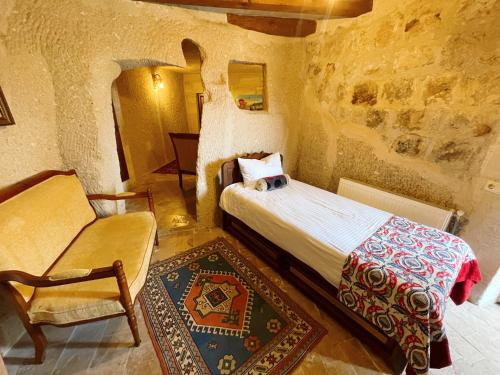 a bedroom with a bed and a chair in a building at Gedik Cave Hotel in Goreme
