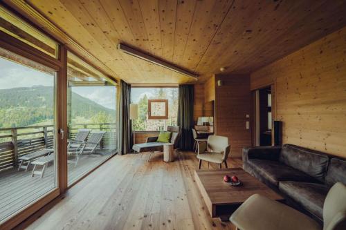 a living room with a couch and a large window at Holzhotel Forsthofalm in Leogang