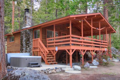 une grande cabane en bois dans les bois avec une cheminée dans l'établissement Acorn Alley Inside Yosemite - Dog Friendly w/Hot tub, Fire pit, EV Charger, à North Wawona