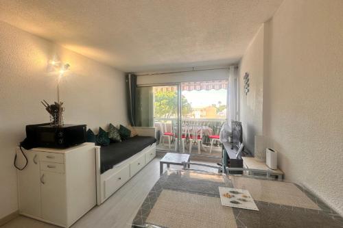 - un salon avec un canapé noir et une fenêtre dans l'établissement La Citadelle du Soleil Appartement au Grau du Roi près de la plage, au Grau-du-Roi