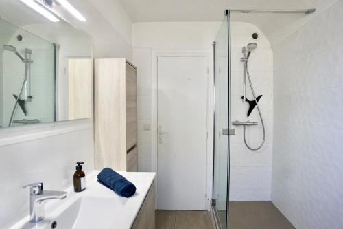 une salle de bain blanche avec une douche et un lavabo dans l'établissement La maison de la rade - 200m de la plage, à Larmor-Plage
