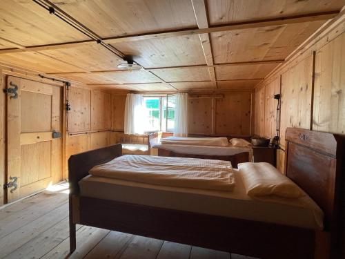two beds in a room with wooden walls at Floras Haus Hostel in Schattwald
