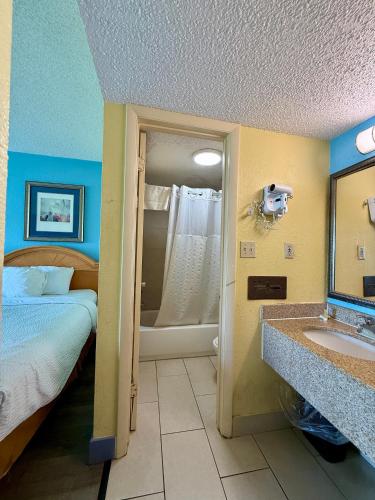 a room with a bed and a bathroom with a sink at Days Inn by Wyndham Ruther Glen Kings Dominion Area in Ruther Glen