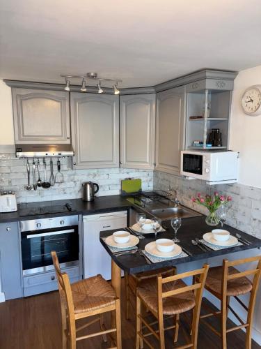 a kitchen with white cabinets and a table with chairs at Georgina Portview- Pet Free-Allergy Friendly in Porthmadog