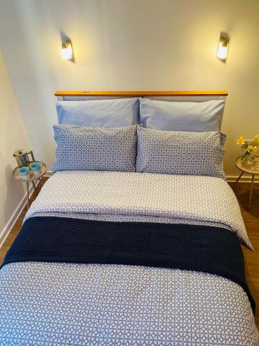 a bed with blue and white sheets and pillows at Georgina Portview- Pet Free-Allergy Friendly in Porthmadog