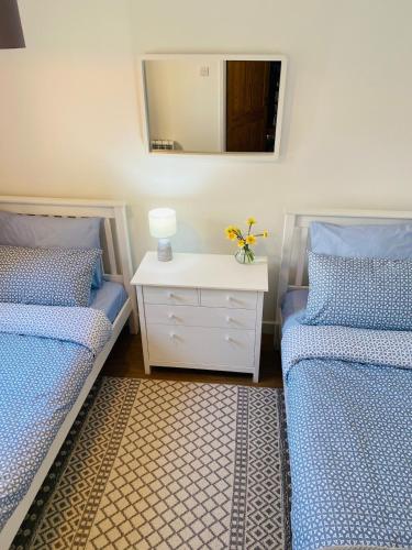 a bedroom with two beds and a mirror on the wall at Georgina Portview- Pet Free-Allergy Friendly in Porthmadog